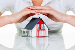 a miniature-scale house being shielded by a persons hands